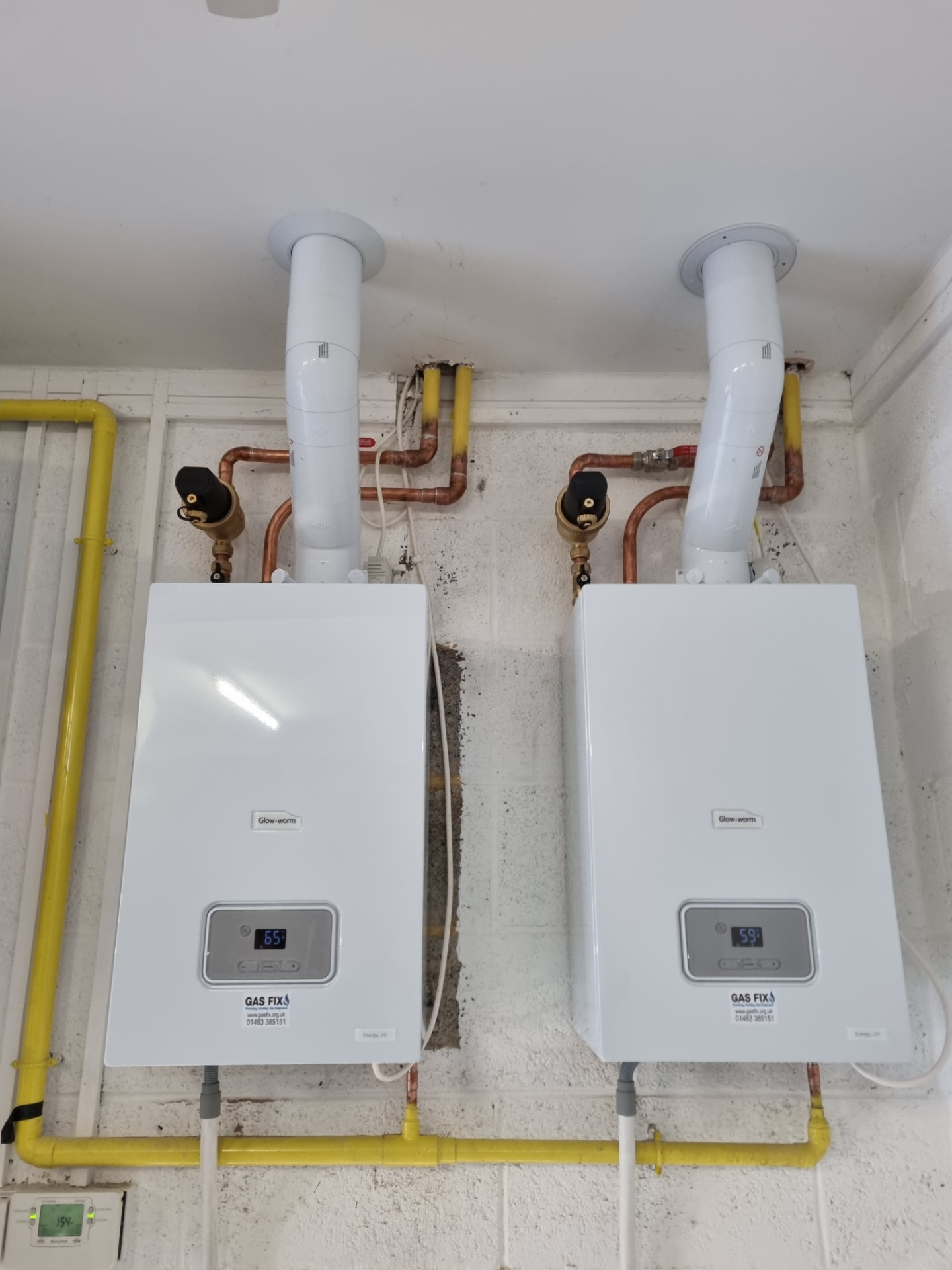 Two Glow-worm boilers wall mounted with gas and flue pipework